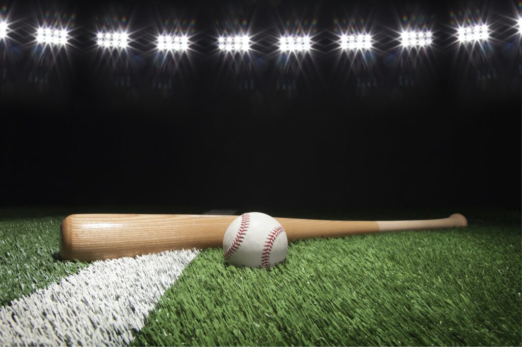 Baseball and bat on field under stadium lights at night