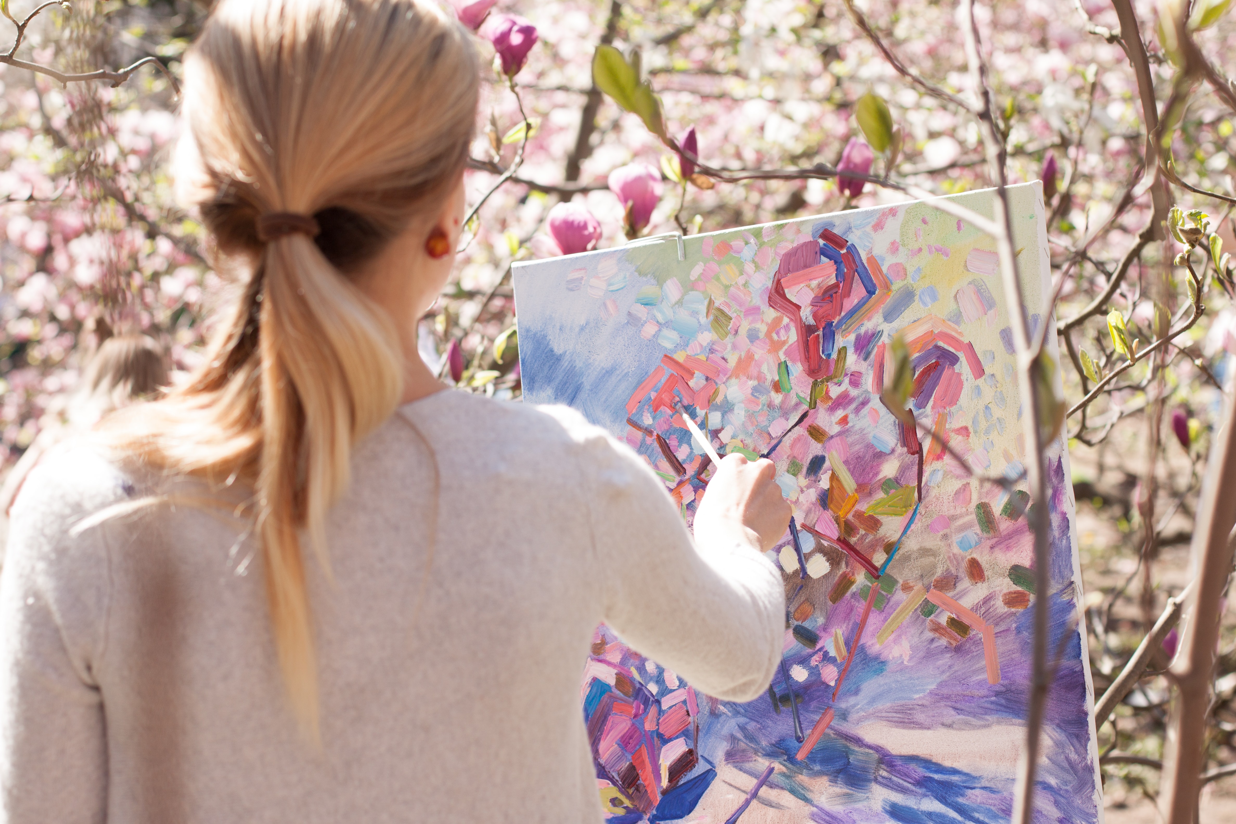 Women painting flowers with trees in the background